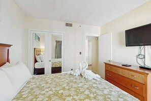 A hotel room with a bed, a dresser, a television, and a door leading to another room. - Palace Resort Unit 710 (Myrtle Beach)