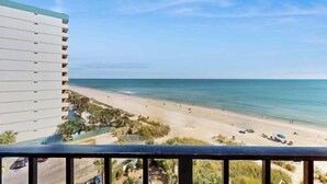 Vista sulla spiaggia da un balcone che si affaccia su una spiaggia sabbiosa e sull'oceano.