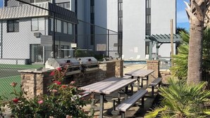 A patio area with outdoor seating and a barbecue grill. - Holiday Towers Unit 501 (Myrtle Beach)