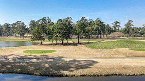 A golf course with sand bunkers, a pond, and trees. - Wild Iris Unit 202 Condo (Myrtle Beach)