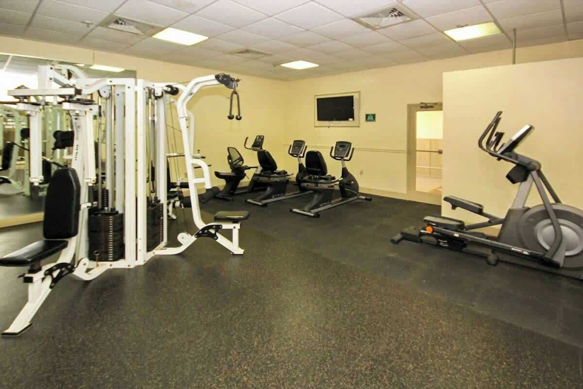 Un gimnasio con diversos equipos de ejercicio, incluyendo cintas de correr, elípticas y máquinas de pesas.