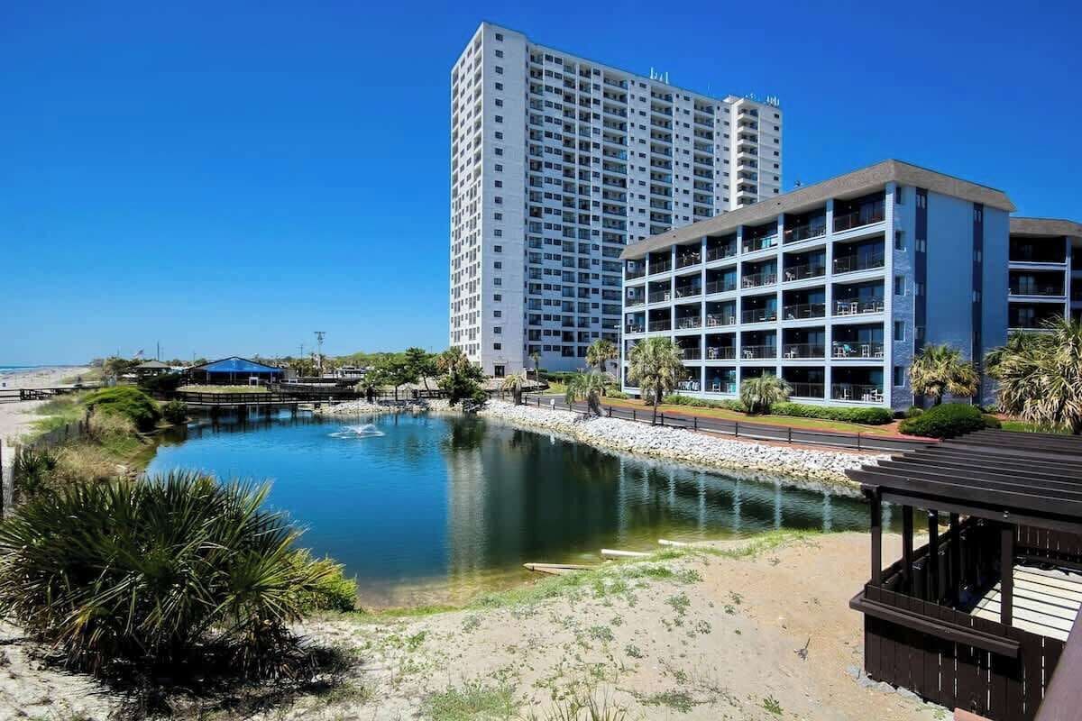 A hotel with multiple floors, a pool, and a beach area.