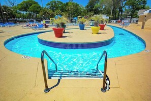 A pool area with a circular design, surrounded by lounge chairs and potted plants. - Beyond the Blue Retreat (Myrtle Beach)