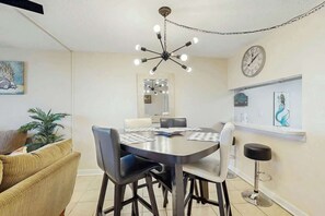 Ein Essbereich mit rundem Tisch, Stühlen, einer Kronleuchter, einer Uhr und einem Barhocker.