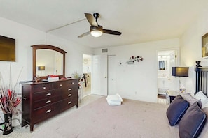 Ein Zimmer mit Deckenventilator, Kommode, Sofa und Spiegel.