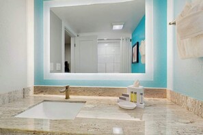 A bathroom with a large mirror, a sink, and a towel rack. - Grande Cayman Unit 413 (Myrtle Beach)