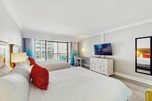 Ein Hotelzimmer mit zwei Betten, einem Fernseher, einem Schreibtisch und einem Balkon mit Blick.