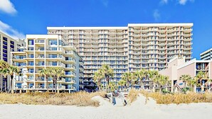 A beachfront hotel with multiple floors, balconies, and palm trees. - Grande Cayman Unit 413 (Myrtle Beach)