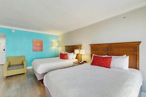 A hotel room with two beds, a bedside table, a lamp, a chair, and a painting on the wall. - Grande Cayman Unit 413 (Myrtle Beach)