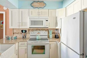 A kitchen with white cabinets, a microwave, a stove, and a refrigerator. - Windy Shores II - 305 (North Myrtle Beach)