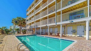 A hotel with a swimming pool, outdoor seating, and a multi-story building with balconies. - Windy Shores II - 305 (North Myrtle Beach)