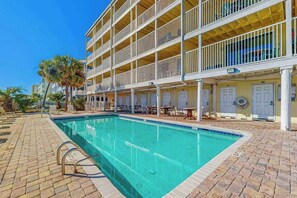 Um hotel com piscina, área de estar ao ar livre e um edifício com várias andares e varandas.