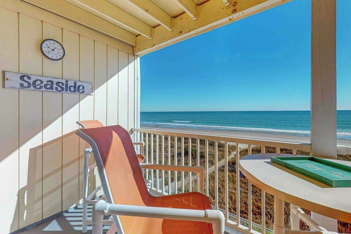 Une vue sur la plage avec un panneau indiquant « Bord de mer », une chaise, une table avec un plateau vert et une horloge au mur.