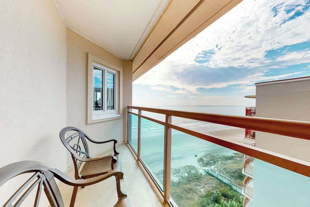 Un balcón con vista al mar, una silla y un ventanal.