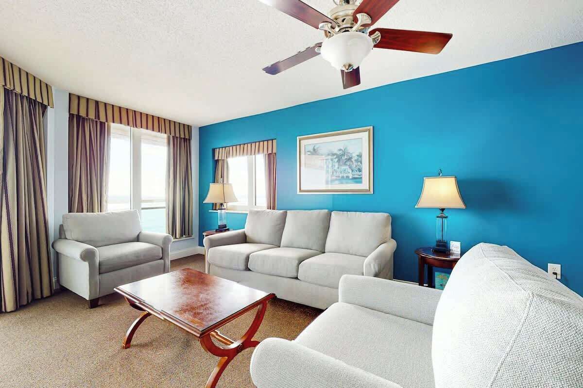 A living room with a blue wall, two sofas, a coffee table, and a ceiling fan.
