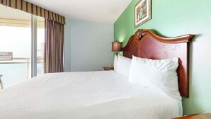 Une chambre d’hôtel avec un grand lit, une table de chevet, une lampe et une vue sur l’extérieur.