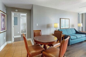 A hotel room with a dining table, chairs, a sofa, and a lamp. - Bahama Sands Unit 1210 (North Myrtle Beach)