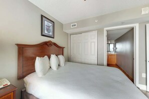 Ein Schlafzimmer mit einem großen Bett, einem Holz-Kopfstück, einem Nachttisch und einem gerahmten Bild an der Wand.