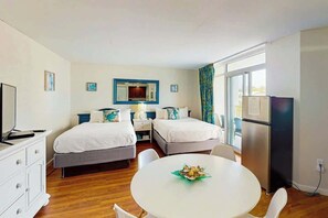 Een hotelkamer met twee bedden, een eettafel, een televisie en een koelkast.
