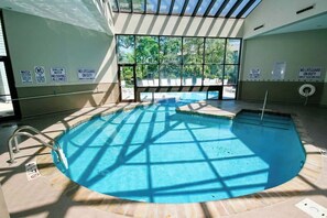 Ein Hallenbad mit Sicherheitshinweisen, freiem Blick ins Freie und gefliestem Boden.