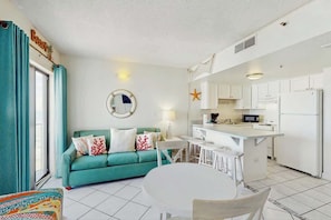 A compact living space with a kitchenette, a sofa, a dining table, and a window with curtains. - Palace Resort Unit 706 (Myrtle Beach)