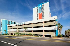 A multi-story parking garage with a prominent 'PALACE' sign, adjacent to a high-rise building with a blue and white color scheme. - Palace Resort Unit 706 (Myrtle Beach)