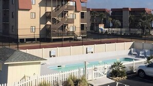En bostadsbyggnad med ett poolområde, inklusive en inhägnad pool och solstolar.