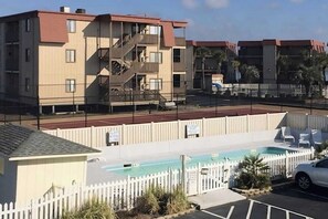 Ein Wohngebäude mit Poolanlage, inklusive umzäuntem Pool und Liegestühlen.