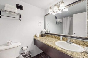 A bathroom with a toilet, sink, mirror, towel rack, and shower curtain. - Landmark Resort Unit 920 (Myrtle Beach)