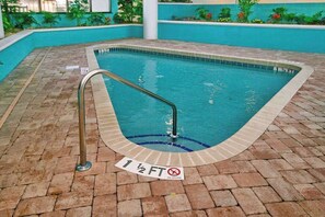 A swimming pool with a tiled edge, a metal ladder, and a sign indicating a depth of 1 1/2 feet. - Landmark Resort Unit 920 (Myrtle Beach)