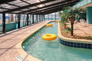 An indoor swimming pool with clear water, a covered walkway, and a small palm tree. - Landmark Resort Unit 920 (Myrtle Beach)