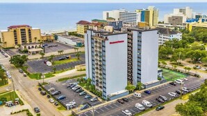 A high-rise hotel with a helipad, parking lot, and a view of the ocean. - Holiday Towers Unit 607 (Myrtle Beach)