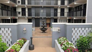 A multi-story building with a central courtyard, a fountain, and flower beds. - Holiday Towers Unit 607 (Myrtle Beach)