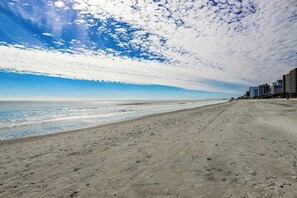 Ein Strand mit blauem Himmel und einer entfernten Stadtlandschaft.