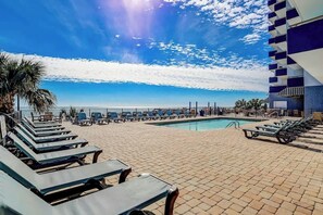 A poolside area with lounge chairs and a view of the ocean. - Bluewater Resort 1006 (Myrtle Beach)