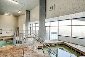 An indoor swimming pool with a tiled floor, metal railings, and large windows. - Bluewater Resort 1006 (Myrtle Beach)