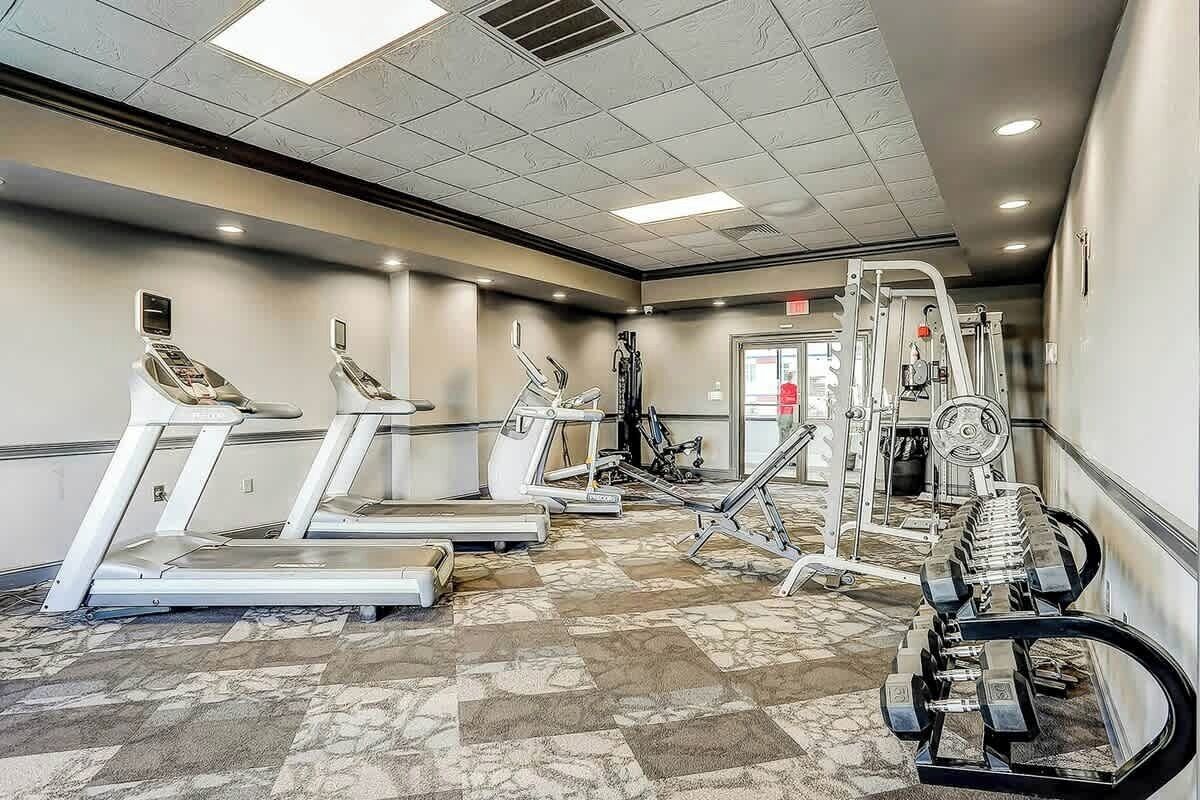 Une salle de sport équipée de tapis de course, de vélos elliptiques et de matériel de musculation.
