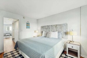 A hotel room with a bed, bedside tables, a wall-mounted sign, and a view of the hallway. - Bluewater Resort 1006 (Myrtle Beach)