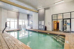 Ein Hallenbad mit klarer Beschilderung, einem gefliesten Boden und Blick auf den angrenzenden Gang.