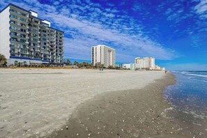 A beachfront hotel with multiple floors, a sandy beach, and a clear sky. - Bluewater Resort 1006 (Myrtle Beach)