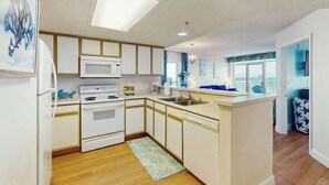 Una cocina moderna con armarios blancos, microondas y estufa.