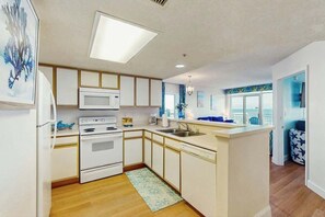 A modern kitchen with white cabinets, a microwave, and a stove.