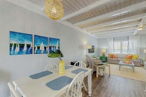 A living room with a dining area, a sofa set, and a large window with curtains. - Ward's Landing Retreat (North Myrtle Beach)