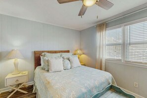 A bedroom with a bed, bedside lamps, a ceiling fan, and a window with blinds. - Ward's Landing Retreat (North Myrtle Beach)
