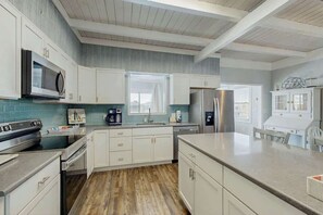 A modern kitchen with white cabinetry, stainless steel appliances, and a wooden floor. - Ward's Landing Retreat (North Myrtle Beach)