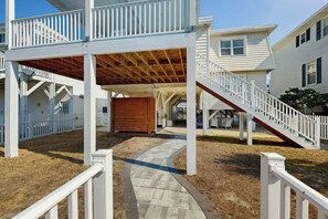 A covered outdoor area with a wooden deck, a white fence, and a pathway leading to a house. - Ward's Landing Retreat (North Myrtle Beach)