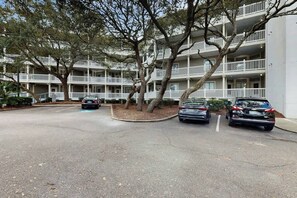A multi-story building with balconies, a parking lot, and trees. - Ocean Creek Unit 2424 (Myrtle Beach)