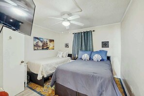 A bedroom with a bed, a TV, a ceiling fan, and artwork on the wall. - Cozy Captains Retreat (North Myrtle Beach)