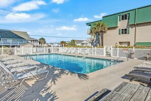 A swimming pool with lounge chairs and a white fence. - Cozy Captains Retreat (North Myrtle Beach)