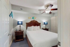 Ein Hotelzimmer mit einem Einzelbett, zwei Nachttischen mit Lampen, einem Deckenventilator und einer Fischdekoration an der Wand.